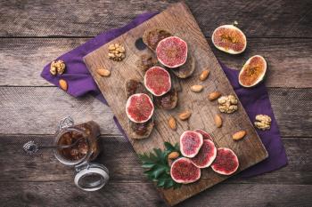 Sliced figs, nuts and bread with jam on choppingboard in rustic style. Autumn season food photo