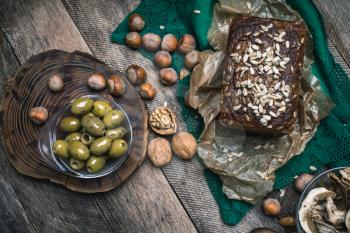 Green olives, nuts mushrooms  and bread with seeds in rustic style