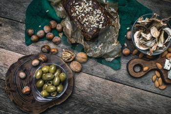 healthy olives, nuts mushrooms  and bread on wood  in rustic style