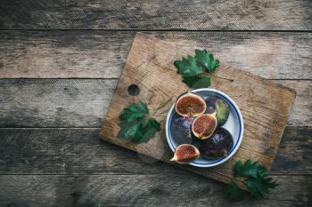 Ripe Figs on cutting board and wooden table. Autumn season food photo