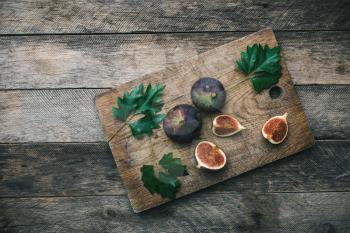Tasty Figs on chopping board and wooden table. Autumn season food photo