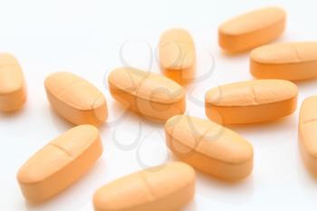 macro of orange pills isolated on white background
