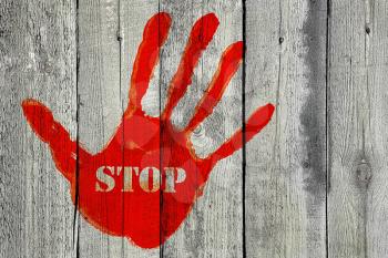 Red handprint with the word ''Stop'' on old wooden fence background