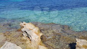 Bright turquoise sea water and coastal rocks, nature background
