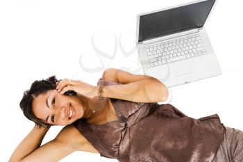 Royalty Free Photo of a Woman Laying on the Floor Talking on her Cell Phone with a Laptop Behind her