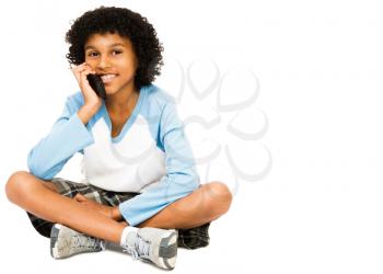 Royalty Free Photo of a Young Boy Sitting Cross Legged on the Floor Talking on a Mobile Phone