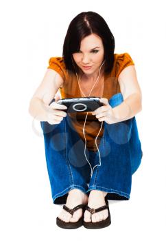 Young woman listening to music on an media player isolated over white