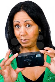 Mid adult woman photographing with a camera and looking surprised isolated over white