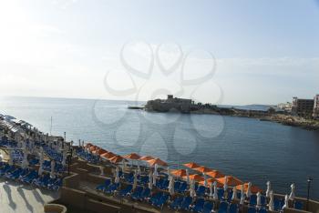 Deck chairs and beach umbrellas at a tourist resort, Malta