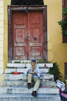 Man sitting on steps and painting, Athens, Greece