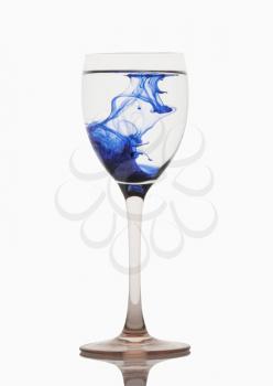 Blue color streaks with water in a wine glass