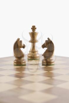 Close-up of chess knights face to face with a chess king on a chessboard