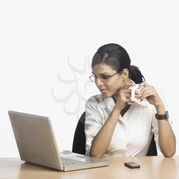 Businesswoman working on a laptop and drinking coffee