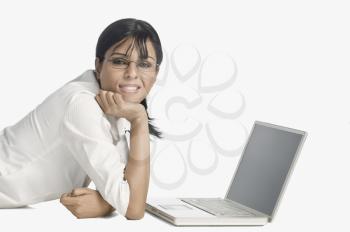 Woman lying in front of a laptop and smiling