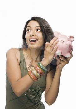 Young woman shaking a piggy bank