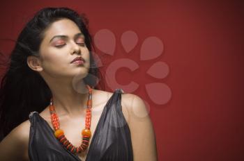 Female fashion model with her eyes closed against red background