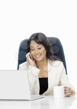 Businesswoman talking on a mobile phone and using a laptop