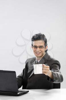Businessman working at a laptop and holding a coffee cup