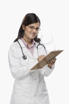Female doctor writing on a clipboard and smiling