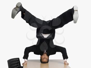 Businessman doing headstand on a conference table