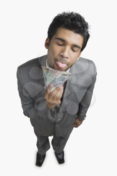 Businessman sticking his tongue out in front of Indian currency notes