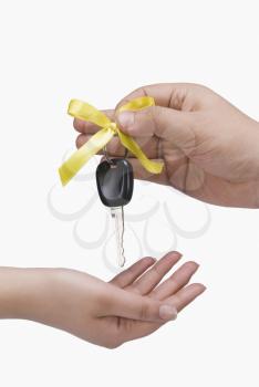 Close-up of a person's hand giving a car key to another person