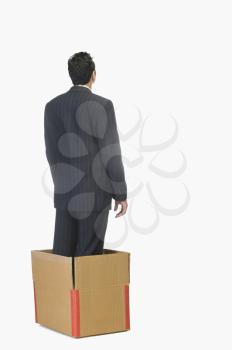Businessman standing inside a cardboard box