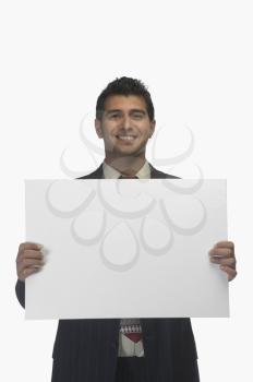 Portrait of a businessman holding a blank placard and smiling