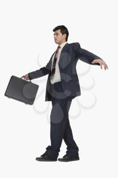 Businessman holding a briefcase and walking carefully
