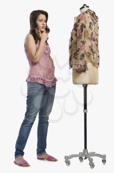 Female fashion designer standing near a mannequin and thinking
