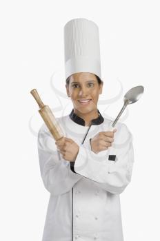 Female chef holding a rolling pin and a ladle