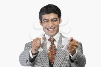 Businessman smiling and tearing a sheet of paper