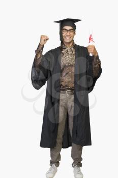 Portrait of a businessman in a graduation gown holding a diploma