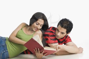 Couple lying on the floor and reading a book