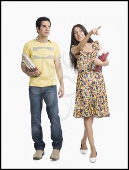 Woman holding books and pointing away beside her boyfriend