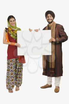 Portrait of a Sikh couple holding a blank placard