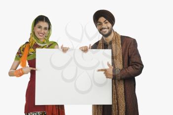 Portrait of a Sikh couple holding a blank placard