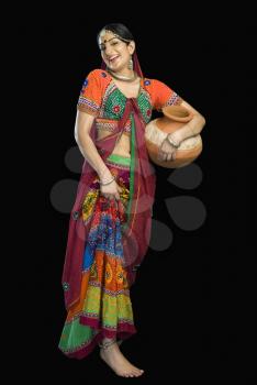 Beautiful woman in colorful lehenga choli carrying water pot