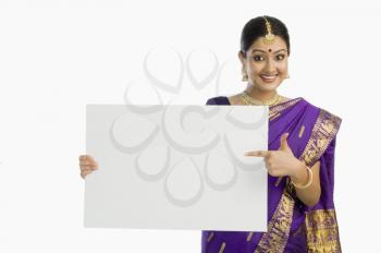 Beautiful woman in traditional Assamese dress holding a blank placard and smiling