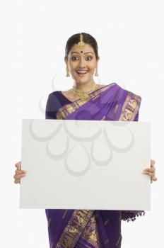 Woman in traditional Assamese dress holding a blank placard and smiling