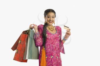 Happy woman holding shopping bags with a credit card
