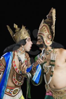 Two men dressed-up as Rama and Ravana and reading text message