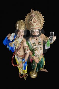 Two stage artists dressed-up as Rama and Ravana and holding mobile phones