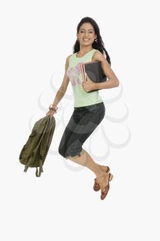 University student jumping with bag and books