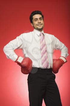 Portrait of a businessman wearing boxing gloves and standing with arms akimbo