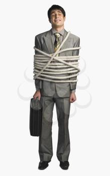 Businessman tied up with ropes and holding a briefcase