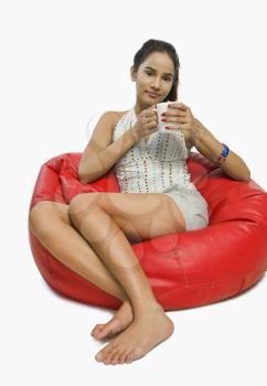 Woman sitting on a bean bag with a cup of coffee