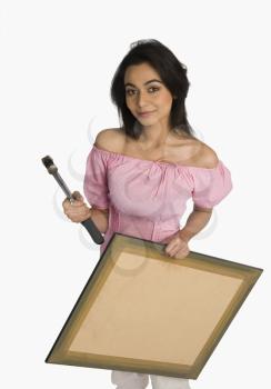 Portrait of a woman holding a hammer and a picture