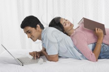 Man using a laptop with his girlfriend sleeping on his back