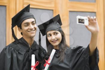 Couple in graduation gown taking a picture of themselves